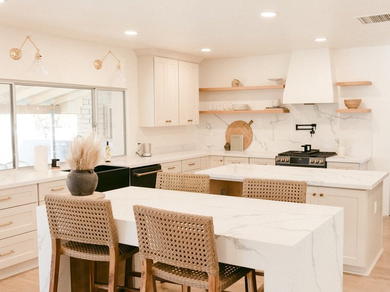 Kitchen with a white waterfall island and sleek white cabinets